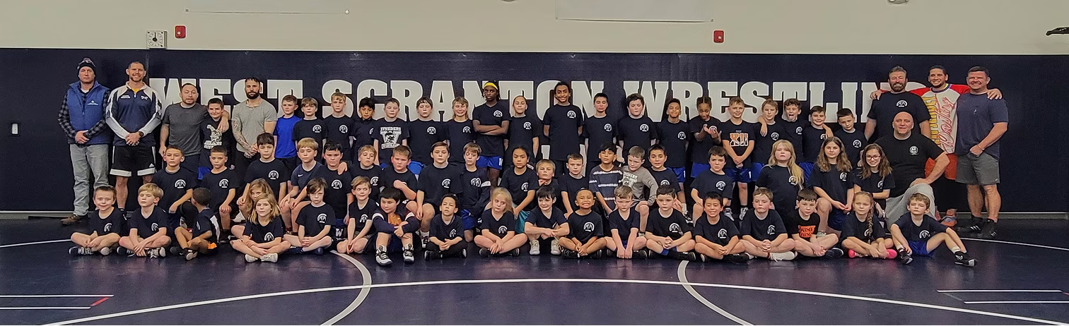 Large group photo in wrestling gym.